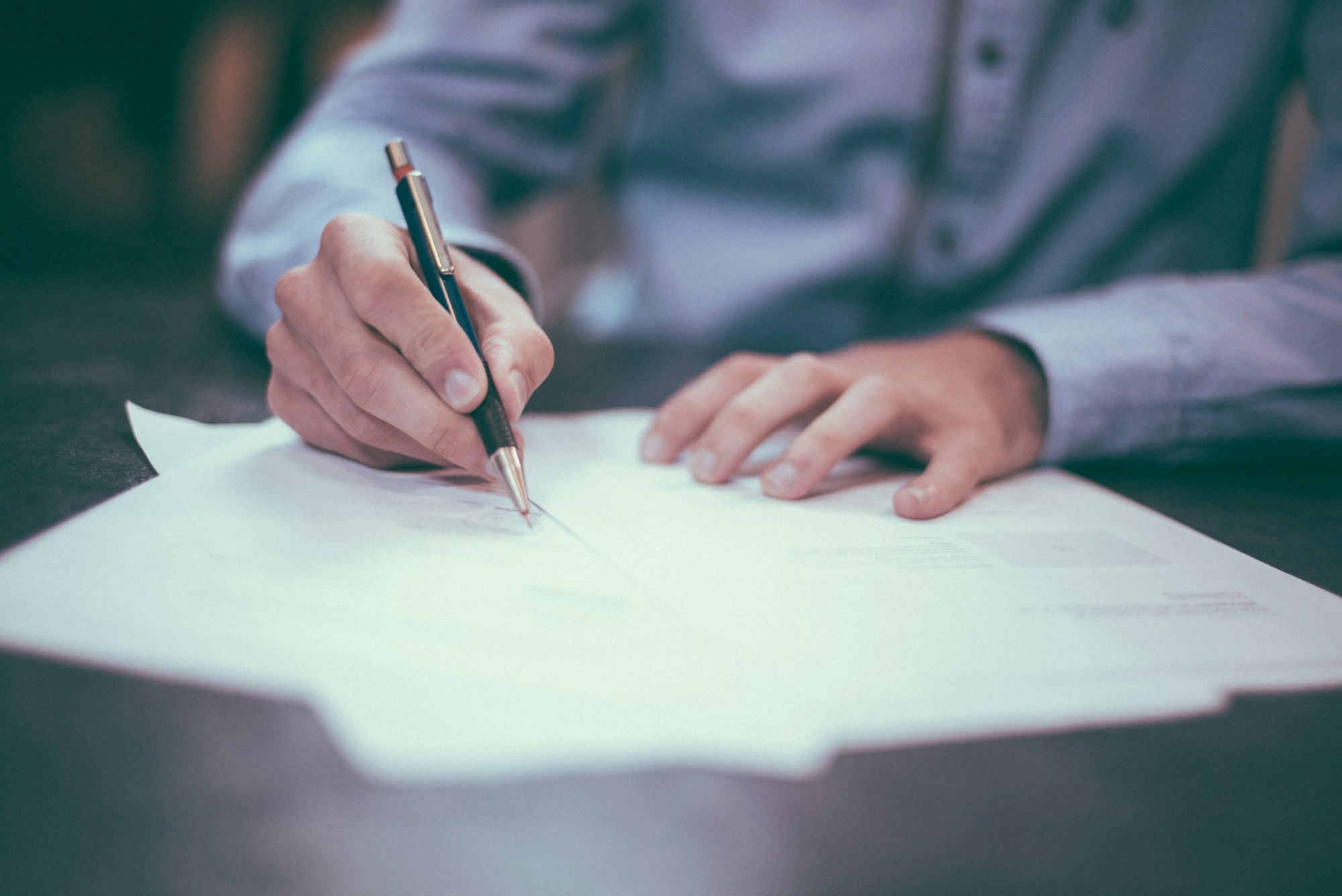 Notarial signing — hand with pen completing a document
